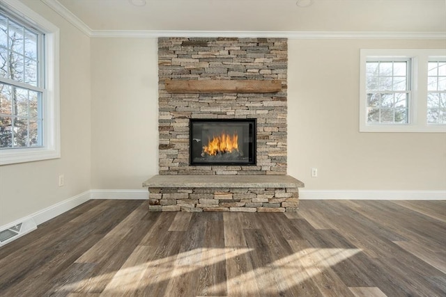 unfurnished living room with a healthy amount of sunlight, a stone fireplace, ornamental molding, and dark wood-type flooring