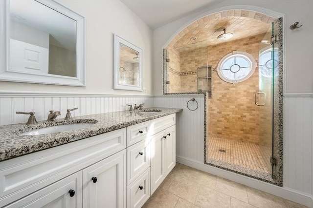 bathroom with a shower with door, vanity, and tile patterned flooring