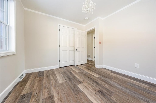 unfurnished room with hardwood / wood-style floors, crown molding, and a chandelier