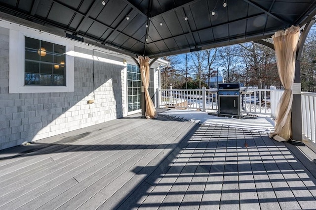 wooden terrace with a gazebo and a grill