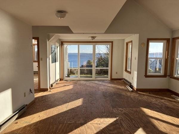 unfurnished living room with a water view, lofted ceiling, and a baseboard heating unit