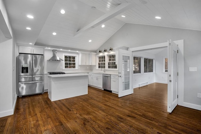 kitchen with stainless steel appliances, light countertops, white cabinets, wall chimney range hood, and a center island