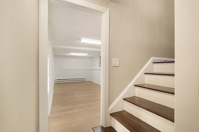 stairway with wood finished floors and a baseboard radiator