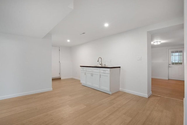 bar with a sink, visible vents, baseboards, and light wood-style floors