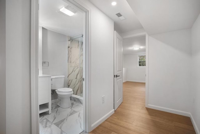 full bath featuring visible vents, toilet, wood finished floors, a marble finish shower, and baseboards