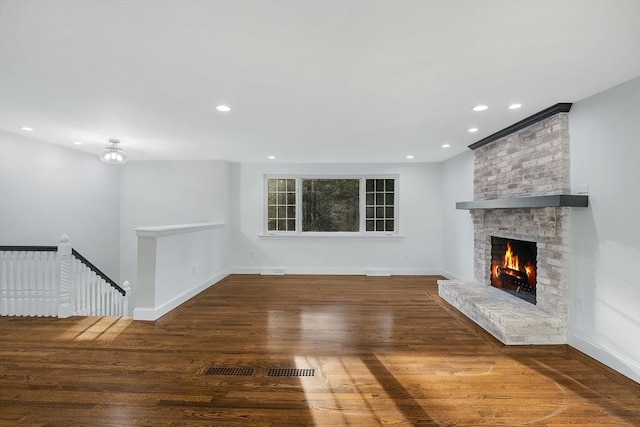 unfurnished living room featuring a fireplace, wood finished floors, and baseboards