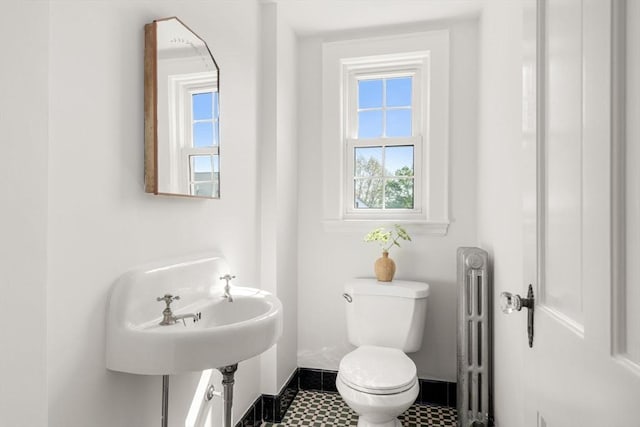 bathroom with healthy amount of natural light, radiator, toilet, and baseboards