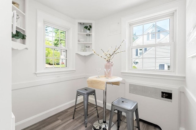 dining area with radiator, wood finished floors, and baseboards