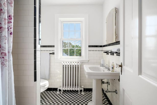 full bath with radiator heating unit, tile walls, toilet, curtained shower, and wainscoting