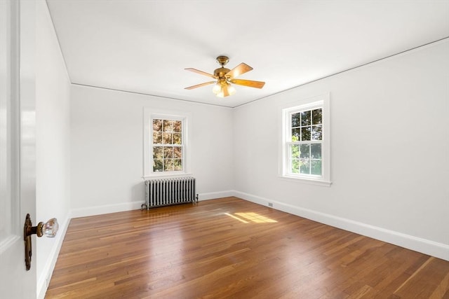 unfurnished room with radiator, wood finished floors, and baseboards