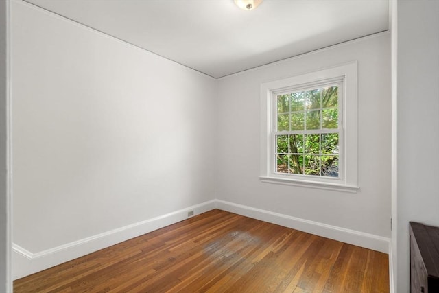 unfurnished room with baseboards and hardwood / wood-style flooring