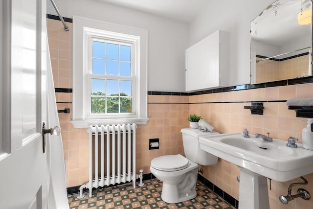 bathroom featuring radiator heating unit, tile walls, toilet, and wainscoting