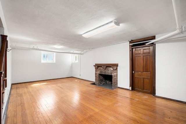 basement featuring a brick fireplace and light wood-style floors