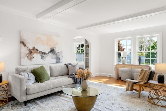 living area with wood finished floors, beamed ceiling, arched walkways, plenty of natural light, and baseboards