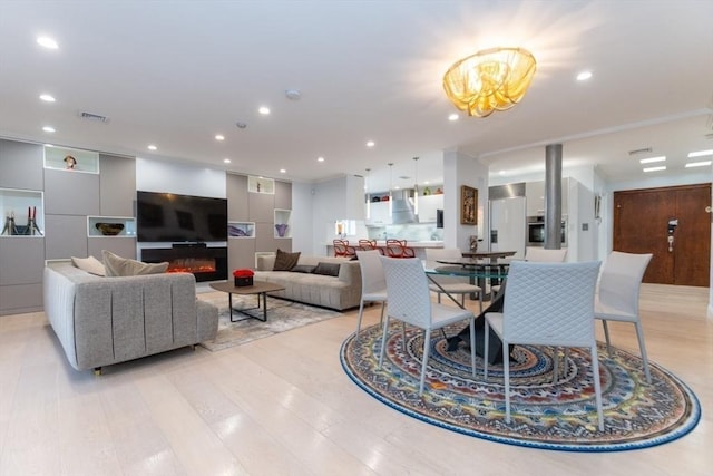 interior space featuring recessed lighting, visible vents, light wood-style floors, and a glass covered fireplace