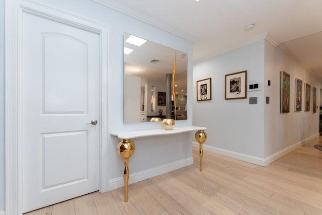 corridor featuring light wood finished floors, visible vents, crown molding, and baseboards