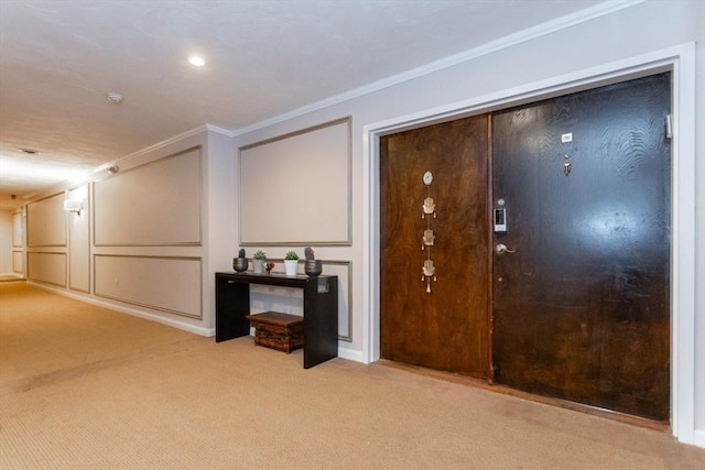 entryway with a decorative wall, carpet flooring, and ornamental molding