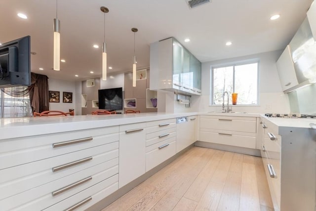 kitchen featuring a sink, light wood-type flooring, light countertops, and white cabinetry