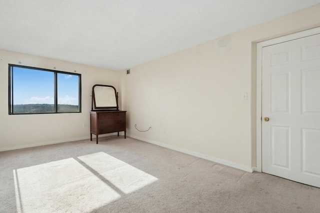 empty room with carpet flooring, visible vents, and baseboards