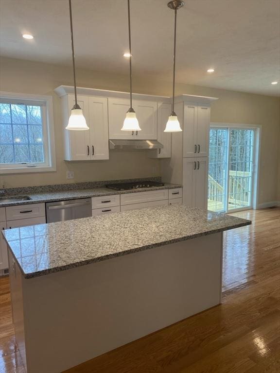 kitchen with a kitchen island, wood-type flooring, hanging light fixtures, appliances with stainless steel finishes, and white cabinets