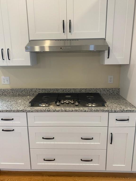 kitchen with white cabinets, stainless steel gas cooktop, and light stone counters