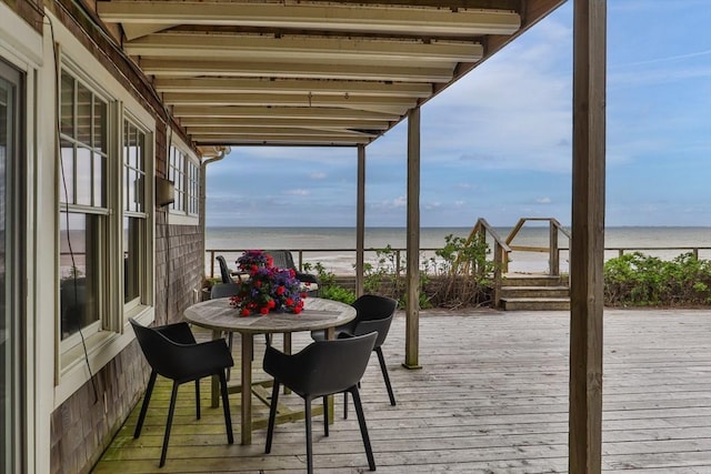 wooden terrace featuring outdoor dining area and a water view