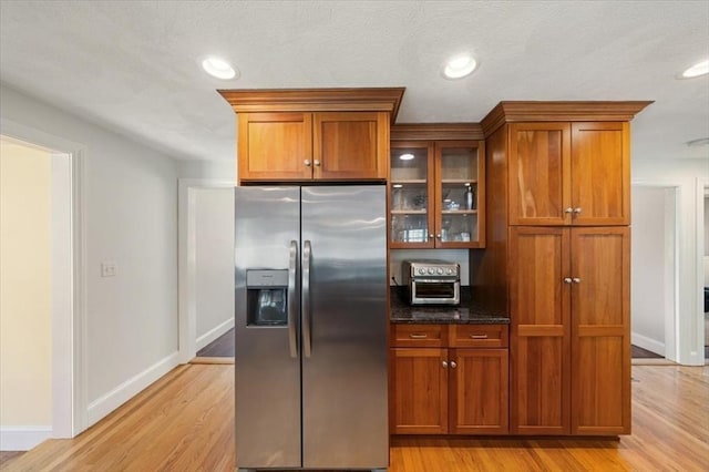76 Union St, Natick, MA 01760 - kitchen featuring stainless steel fridge, glass insert cabinets, brown cabinetry, and light wood finished floors