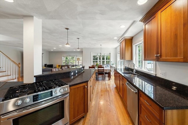 76 Union St, Natick, MA 01760 - kitchen featuring a sink, brown cabinetry, dark stone counters, stainless steel appliances, and light wood-type flooring