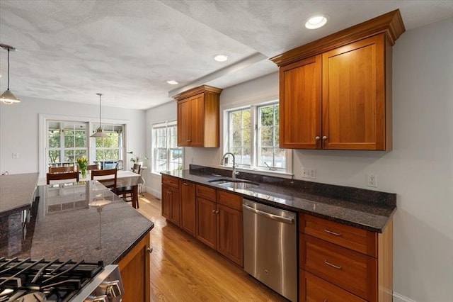 76 Union St, Natick, MA 01760 - kitchen featuring brown cabinets, a sink, light wood-style flooring, dark stone counters, and stainless steel appliances