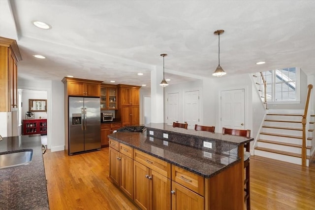 76 Union St, Natick, MA 01760 - kitchen with brown cabinetry, a sink, a breakfast bar, and stainless steel appliances