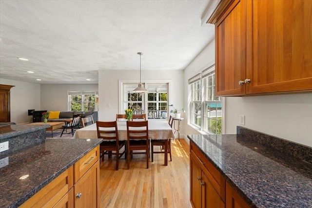 76 Union St, Natick, MA 01760 - kitchen featuring brown cabinetry, pendant lighting, recessed lighting, dark stone counters, and light wood finished floors