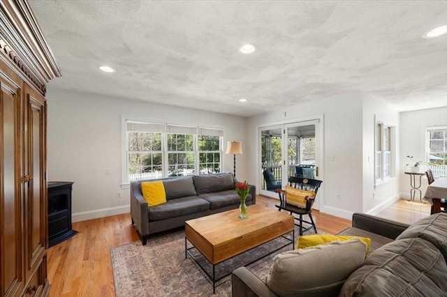 76 Union St, Natick, MA 01760 - living room with a wood stove, a textured ceiling, recessed lighting, baseboards, and light wood-type flooring