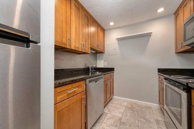 103 Grove St Unit 317, Rockland, MA 02370 - kitchen with appliances with stainless steel finishes, baseboards, dark stone countertops, decorative backsplash, and brown cabinetry