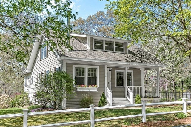 bungalow-style home featuring a porch, a fenced front yard, and a shingled roof