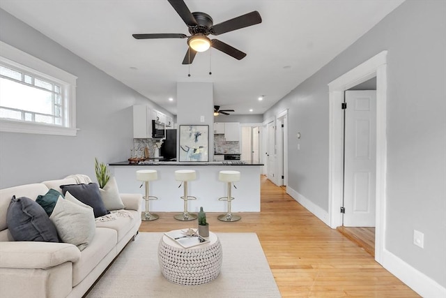 living area featuring ceiling fan, light wood-style floors, baseboards, and recessed lighting