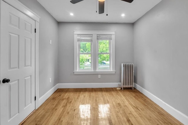 empty room featuring radiator, ceiling fan, baseboards, light wood-style flooring, and recessed lighting