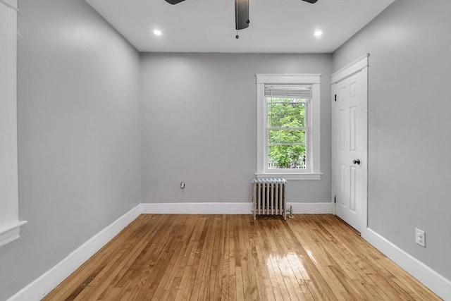 empty room featuring radiator, light wood-style flooring, ceiling fan, baseboards, and recessed lighting