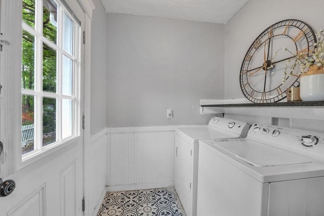 washroom featuring washer and clothes dryer, plenty of natural light, a wainscoted wall, light tile patterned flooring, and a textured ceiling