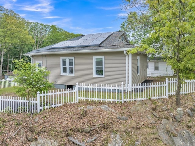 view of home's exterior with a shingled roof and roof mounted solar panels