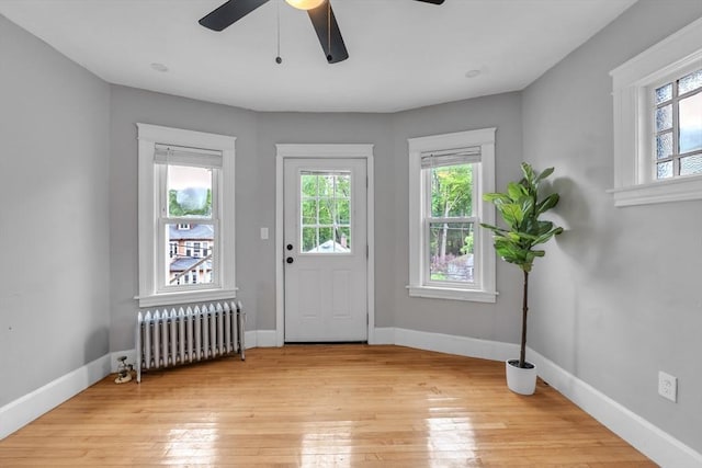 doorway to outside with radiator, plenty of natural light, ceiling fan, and light wood-style flooring
