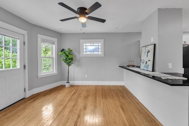 foyer entrance featuring baseboards, ceiling fan, and light wood finished floors