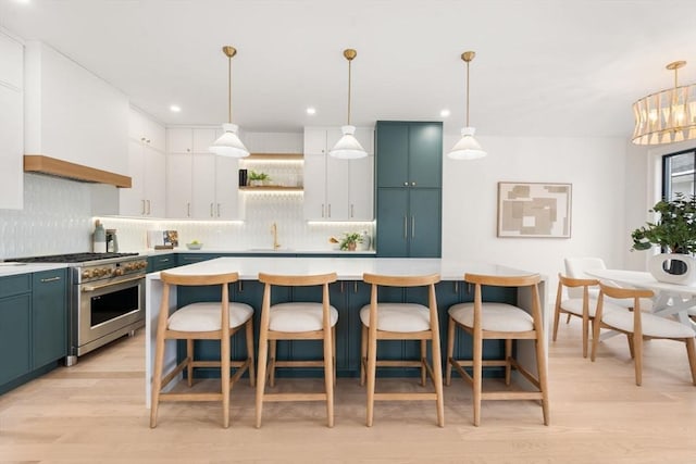 kitchen with a kitchen island, white cabinets, high end range, and decorative light fixtures