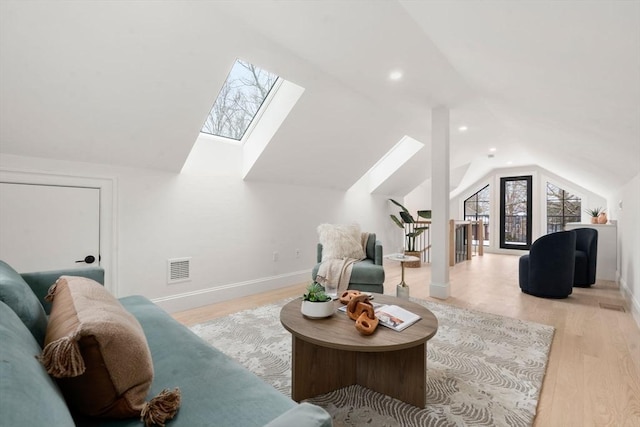 living room with lofted ceiling with skylight and light hardwood / wood-style flooring