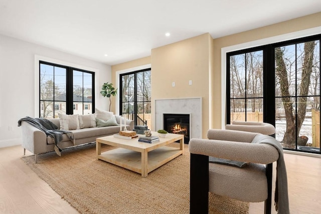 living room featuring a high end fireplace and light wood-type flooring