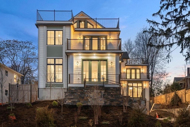 back house at dusk featuring a balcony