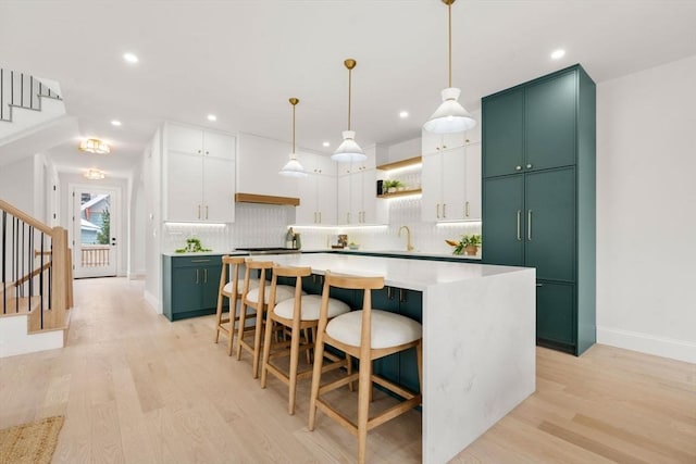 kitchen with hanging light fixtures, light hardwood / wood-style floors, a center island, and white cabinets