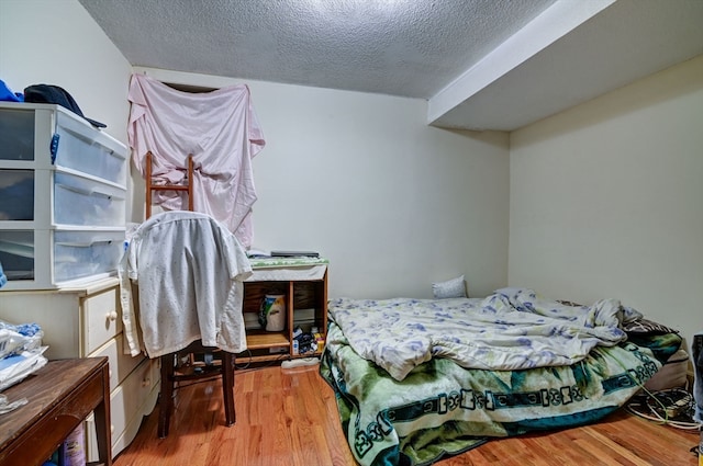 bedroom with a textured ceiling and wood-type flooring