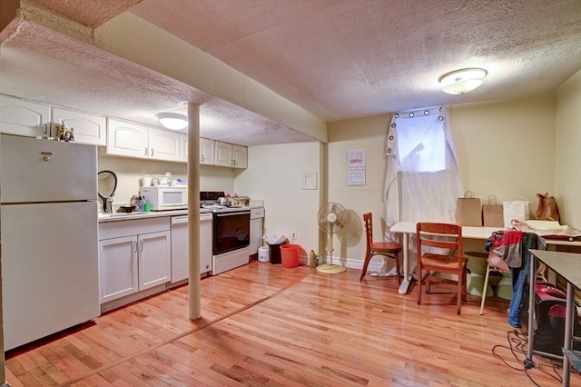 kitchen with light wood-type flooring, a textured ceiling, white appliances, and white cabinets