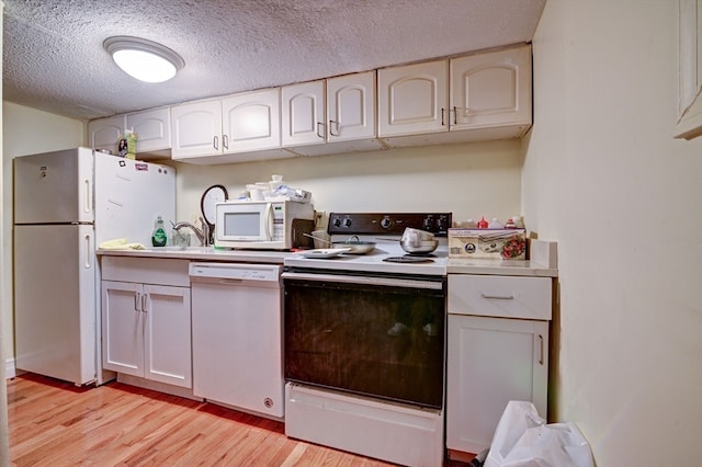 kitchen featuring light wood-type flooring, a textured ceiling, white appliances, and white cabinets