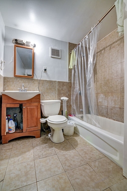 full bathroom featuring tile walls, tile patterned floors, shower / tub combo, vanity, and toilet